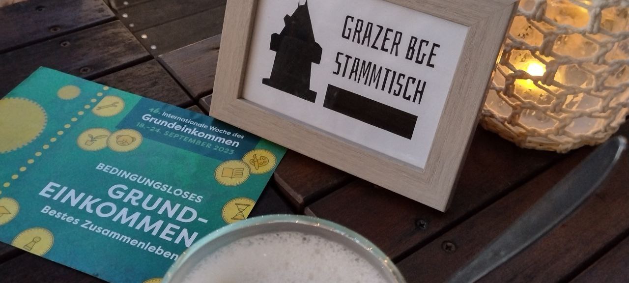 BGE Stammtisch Graz Tisch mit Kaffee und eingerahmtem Logo in gemütlicher Atmosphäre.